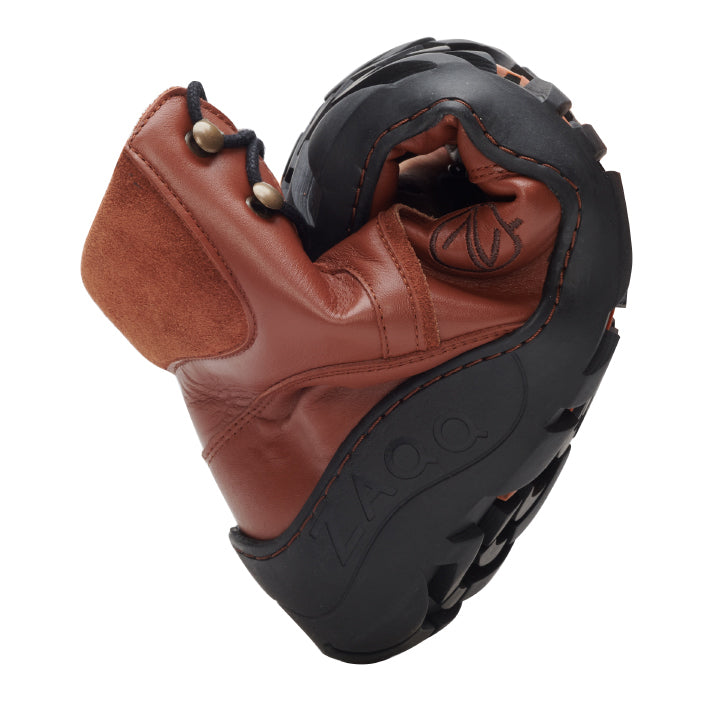 The cognac-colored TERRAQ Winter Waterproof shoes from ZAQQ can be effortlessly folded in half to reveal their flexible sole and luxurious nappa leather finish. The brand name ZAQQ can be clearly seen on the sole. This lace-up model with black laces offers both comfort and style for any casual occasion.