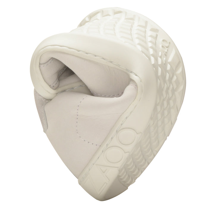 The sole of the QOMFY Wide White sneaker is curved in a spiral shape, showing its flexibility. The textured pattern and the brand name ZAQQ are visible and emphasize comfort and adaptability.