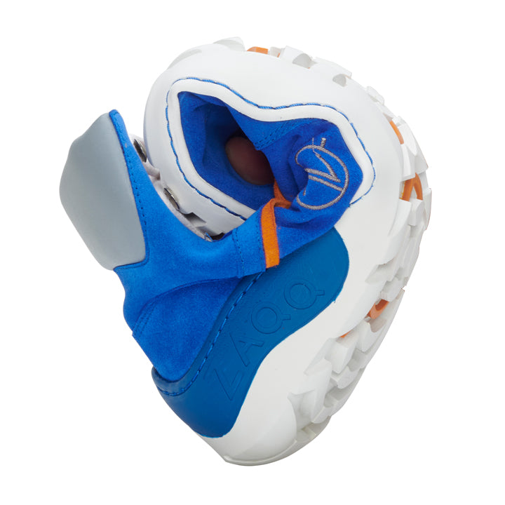 Introducing the TREQ Azure Waterproof from ZAQQ, a vibrant sneaker with a bold, twisted design and a sturdy, sophisticated sole reminiscent of the acclaimed ZAQQ TERRA sole reminds. This shoe features a striking blue and white color scheme with orange accents and heart-shaped patterns. Its uniquely textured sole is perfect for outdoor adventures.