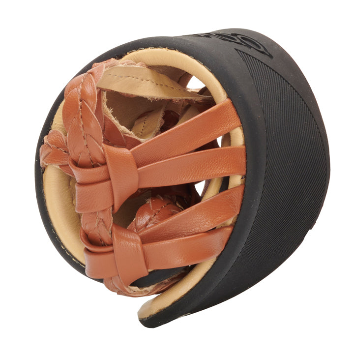 A close-up of a pair of QALMA cognac sandals from ZAQQ, made from luxurious brown nappa leather. The sandals are rolled up in a black, round travel case. They feature braided straps for added elegance and comfort, while the case features a textured design on the outside.
