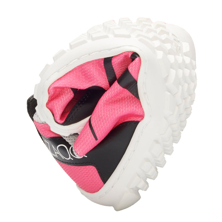 The picture shows the SQIM Pink, a sustainable barefoot shoe from ZAQQ, in pink and black with a white textured sole curved in the middle to highlight its flexibility, made from recycled fibers.