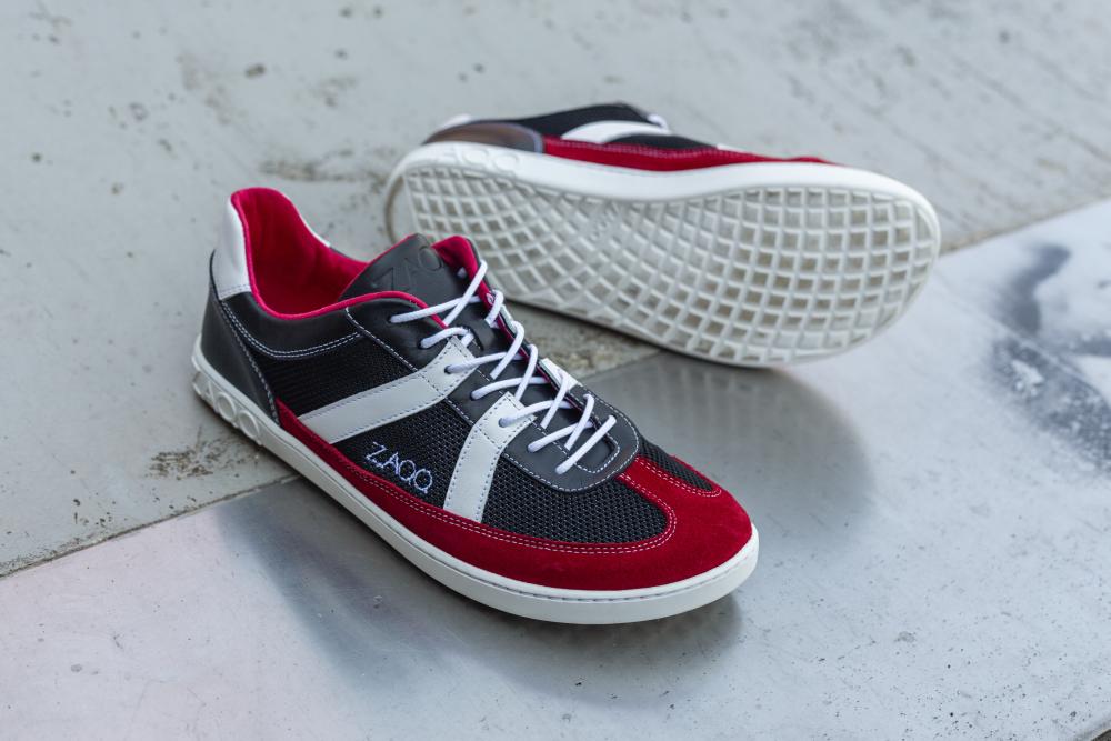 A pair of stylish ones ZAQQ-Sneaker, the OAQLEY Red, with a bright red, black and white design. These shoes feature crisp white laces and subtle branding to the side, elegantly presented on a textured concrete surface.