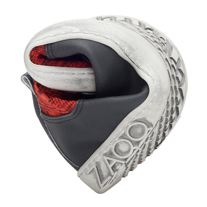 A white and gray sneaker from ZAQQ called QRIS Red is artfully curved into a spiral shape reminiscent of a heart. Featuring red and black knit fabric on the inside, this sneaker embodies the essence of QRIS Red.