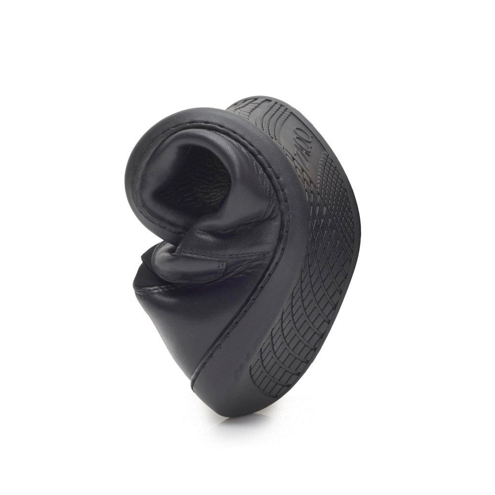 The SELEQT Stretch Black slipper from ZAQQ bends to demonstrate its flexibility. Its sole features a textured pattern for better grip. Positioned vertically on a plain white background, it emphasizes the shoe's flexible and durable design.