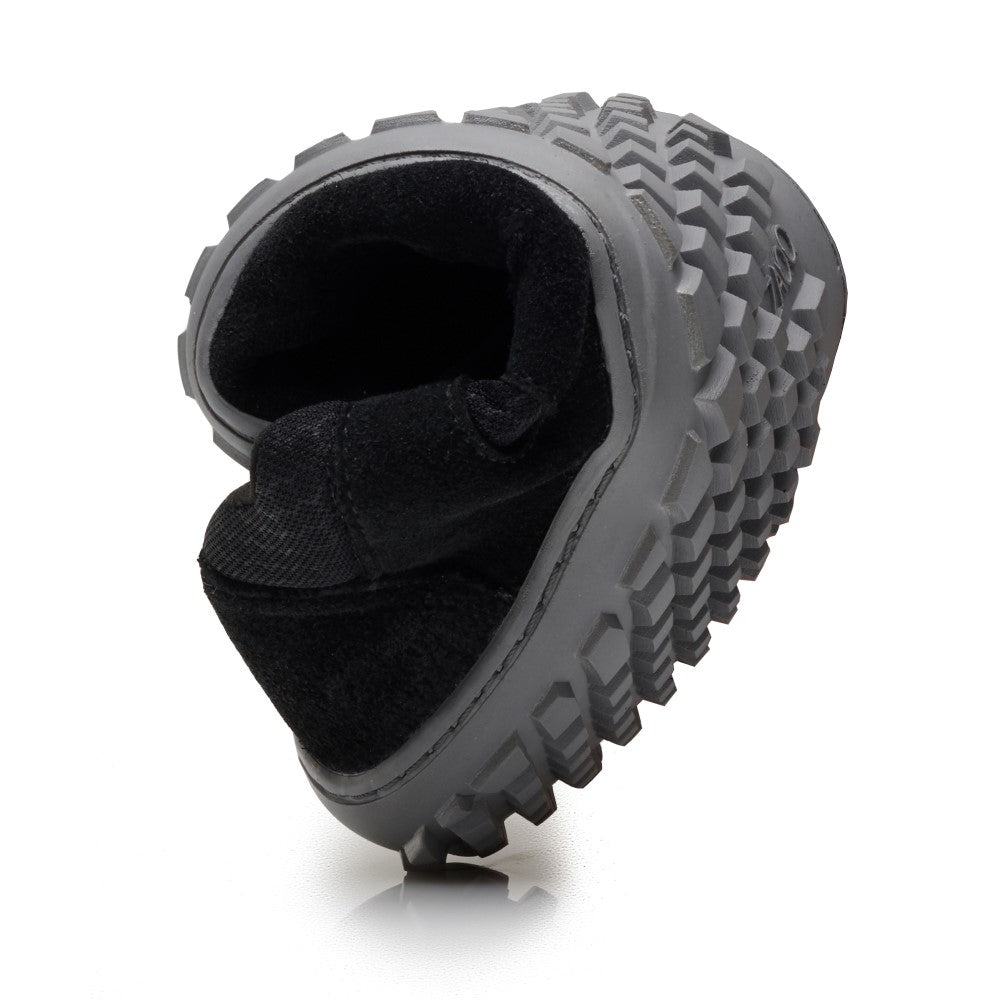 The SHOQQ Black from ZAQQ is a black boot with a thick, sturdy sole with a geometric tread pattern on a white background to highlight its robust design. This versatile vegan barefoot shoe is ideal for anyone looking for both durability and a barefoot feel on their outdoor adventures.