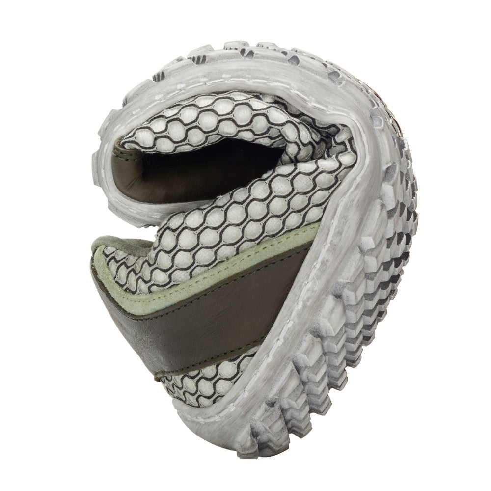 A close-up of a light green TOQIO sneaker from ZAQQ shows its flexibility. The sole curves upward to reveal a honeycomb interior and a textured outsole. The shoe is breathable and designed in a mix of white and gray tones accented by touches of light green.