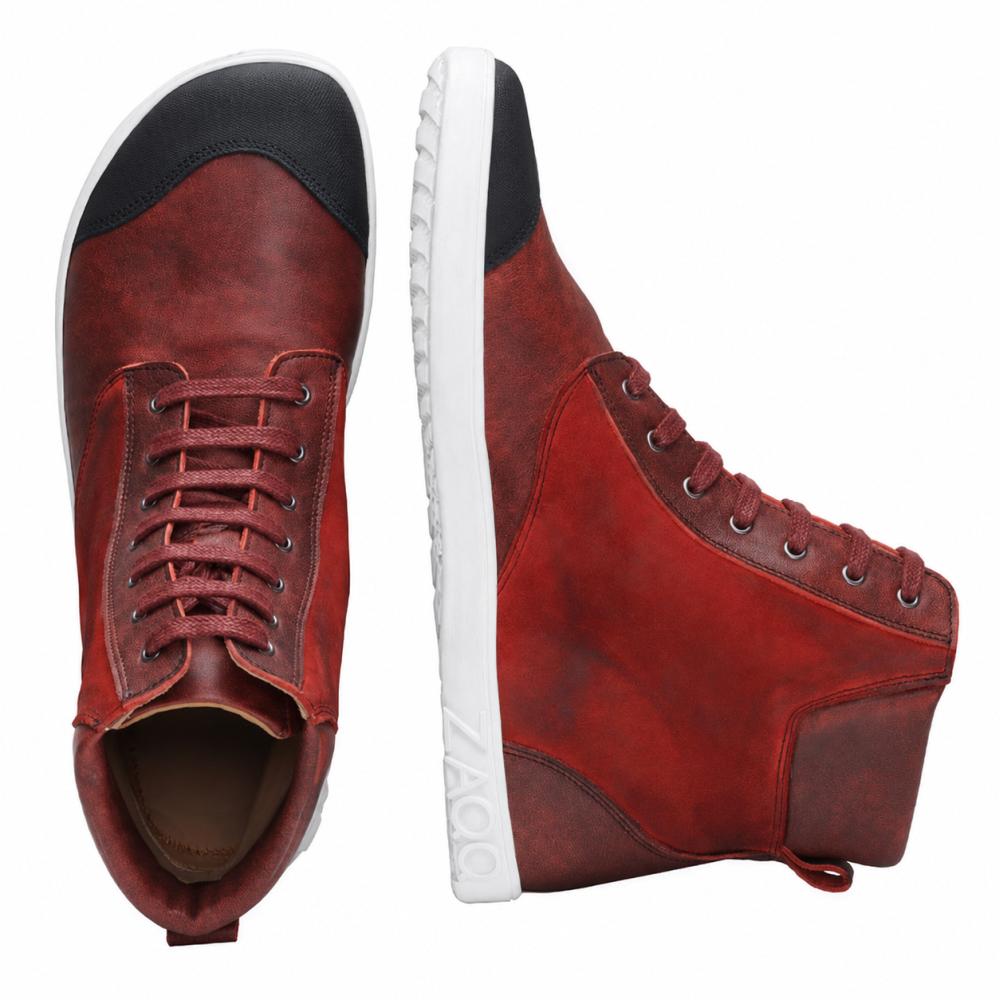 The CHICAQO Red by ZAQQ is a pair of high-top sneakers made from nappa and suede leather with a black toe cap and a white, flexible sole. One shoe is displayed upright for a side view, while the other highlights its laces and the black front detail from above. The brand name ZAQQ is visible on the sole.