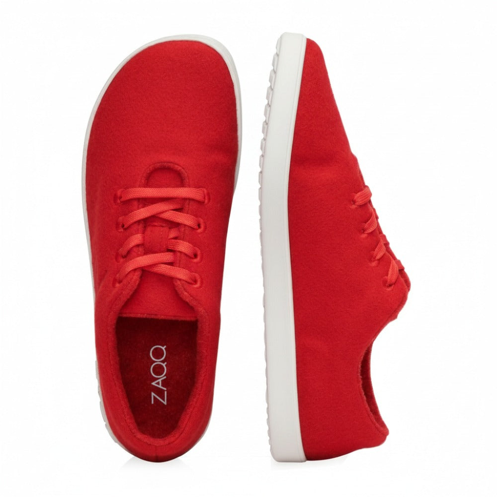 Ein Paar rote lässige LIQE Race-Sneaker von ZAQQ mit Gummisohle. Ein Schuh ist von oben zu sehen und zeigt die Schnürsenkel, während der andere von der Seite zu sehen ist und die Sohle mit der Aufschrift ZAQQ hervorhebt. Der schlichte weiße Hintergrund betont das elegante Design und die bequeme Barfußsohle.