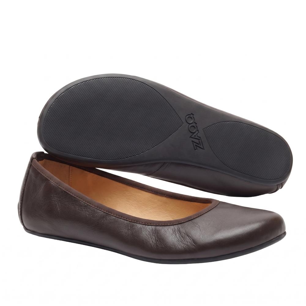 Ein Paar elegante dunkelbraune QARMA-Ballerinas von ZAQQ, wobei ein Schuh auf der Seite liegt, sodass die Sohle sichtbar ist, und der andere aufrecht steht, um die abgerundete Spitze und das tief ausgeschnittene Design hervorzuheben. Das hellbraune Innenfutter verleiht diesen von Barfuß-Ballerinas inspirierten Ballerinas eine elegante Note.