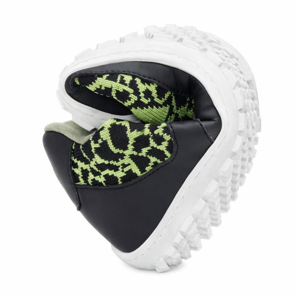 Ein Paar QASEY Green-Schuhe von ZAQQ mit einem schwarz-grünen Muster, aus veganen Materialien mit dicken weißen Sohlen gefertigt, sind zu einer Herzform gefaltet, um ihre Flexibilität zu demonstrieren.