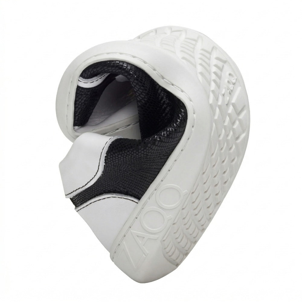 Eine flexible, in der Mitte gebogene Schuhsohle zeigt das Profilmuster dieses Barfuß-Sneakers. Die weiße Laufsohle trägt deutlich den Markennamen ZAQQ, während der obere Teil des QODY White-Schuhs in Schwarz und Weiß kontrastiert.