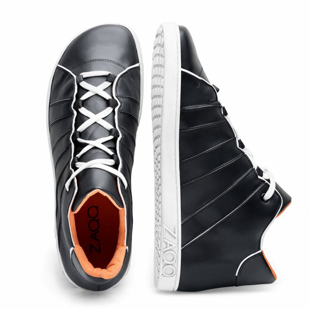 Wir präsentieren den QQQ Mid Black White von ZAQQ: ein Paar eleganter und moderner schwarzer Sneaker aus Nappaleder mit weißen Schnürsenkeln und Sohlen. Ein Schuh steht aufrecht und zeigt das Seitendesign sowie das ZAQQ-Branding auf der Innenseite, während der andere Schuh geneigt ist, um seinen einzigartigen Barfußschuh-Stil hervorzuheben.