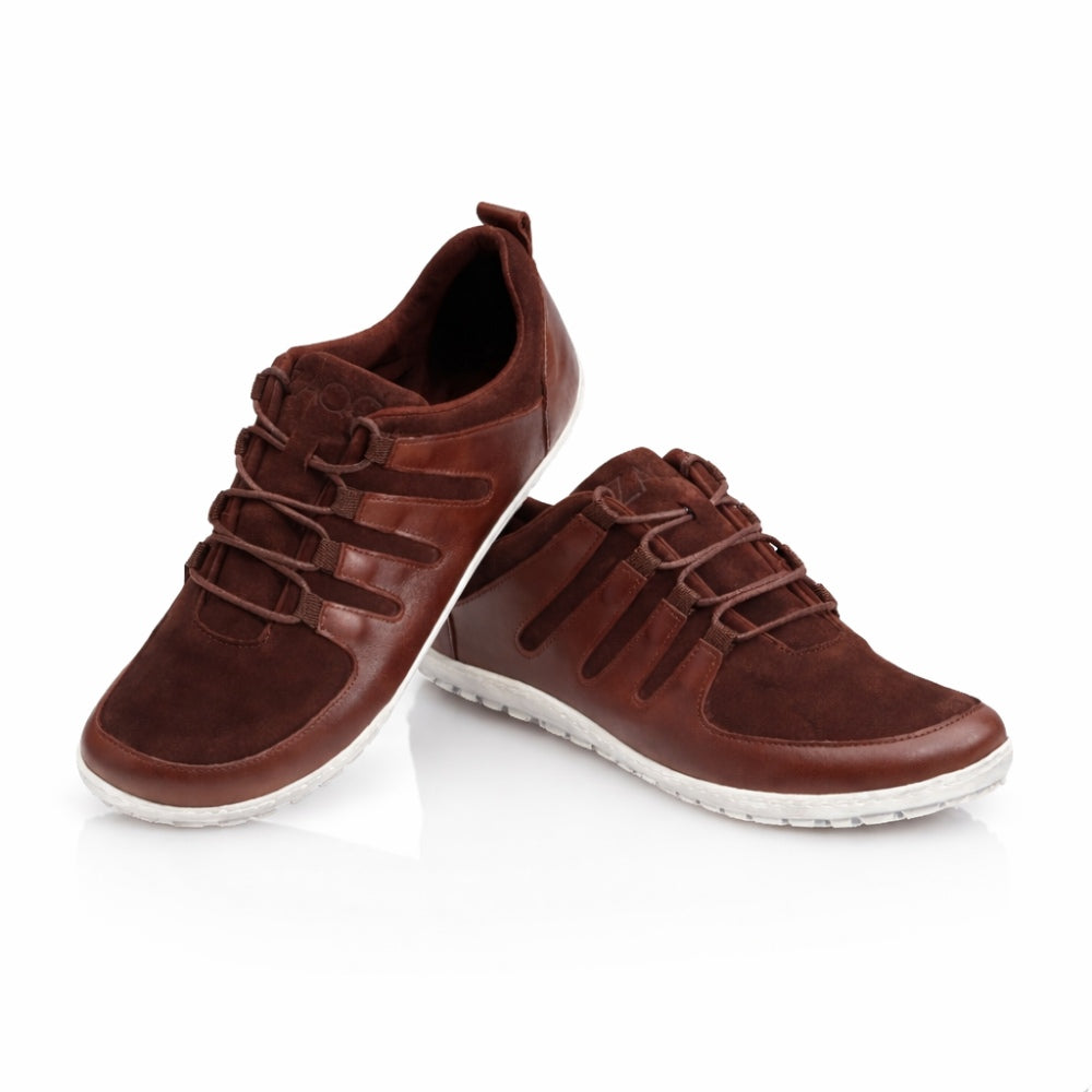Die SHOQQ Dark Brown Sneaker von ZAQQ bestehen aus Leder mit Wildlederakzenten und einem markanten Schnürdesign, ergänzt durch Gummisohlen, die einen starken Kontrast zum weißen Hintergrund bilden. Diese Elemente verleihen dem Sneaker einen lässigen und dennoch stilvollen Look und machen ihn zu einem idealen Barfußschuh für jeden Anlass.
