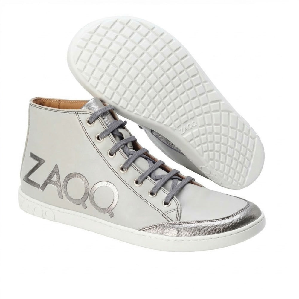 Wir präsentieren den SQYLA Grey von ZAQQ, ein Paar High-Top-Sneaker aus Nappaleder. Diese stylischen Schuhe haben graue Schnürsenkel, eine auffällige silberne Zehenkappe und das auffällige ZAQQ-Logo der Marke an der Seite. Sie sind mit einer Kautschuksohle für hervorragenden Halt ausgestattet und verfügen über eine weiße Basis, ergänzt durch metallische Akzente für ein elegantes und modernes Erscheinungsbild.