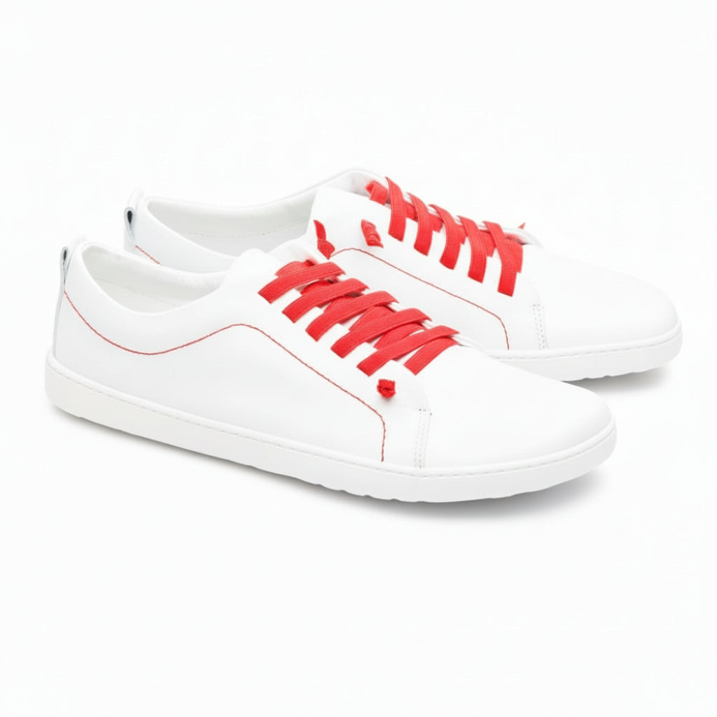 Wir präsentieren den STIQ White von ZAQQ, ein stylisches Paar Sneaker aus hochwertigem Nappaleder. Diese eleganten weißen Schuhe sind mit leuchtend roten Schnürsenkeln und Nähten akzentuiert. Sie haben eine graue, strukturierte Sohle und das dezente ZOO-Logo ist elegant auf der Ferse eingeprägt. Nebeneinander vor einem schlichten weißen Hintergrund präsentiert, verkörpern sie perfekt zeitgenössische Mode.