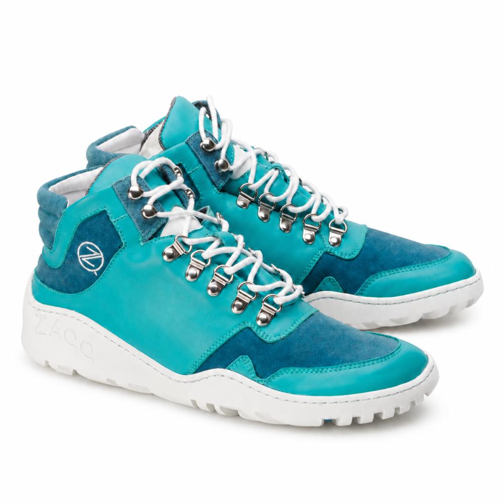 Ein Paar wasserdichte VAQATION Blue High-Top-Sneaker von ZAQQ mit weißen Schnürsenkeln und einer TERRA-Sohle. Diese stylischen Schuhe haben silberne Ösen und ein kleines rundes Logo an der Seite und kombinieren glatte und Wildlederoberflächen für zusätzlichen Stil und Komfort.