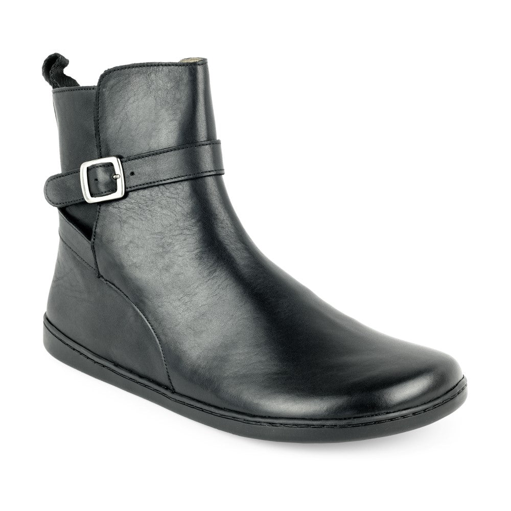 The RIQUET Black Boot from ZAQQ is a stylish strappy boot made from high-quality nappa leather. It features a silver buckle strap on the side and a tab on the back. The smooth surface and flat sole of the boot provide elegance and barefoot comfort.
